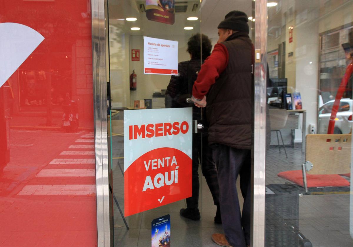 Dos personas entran en una agencia de viajes que anuncia la venta de viajes del Imserso.