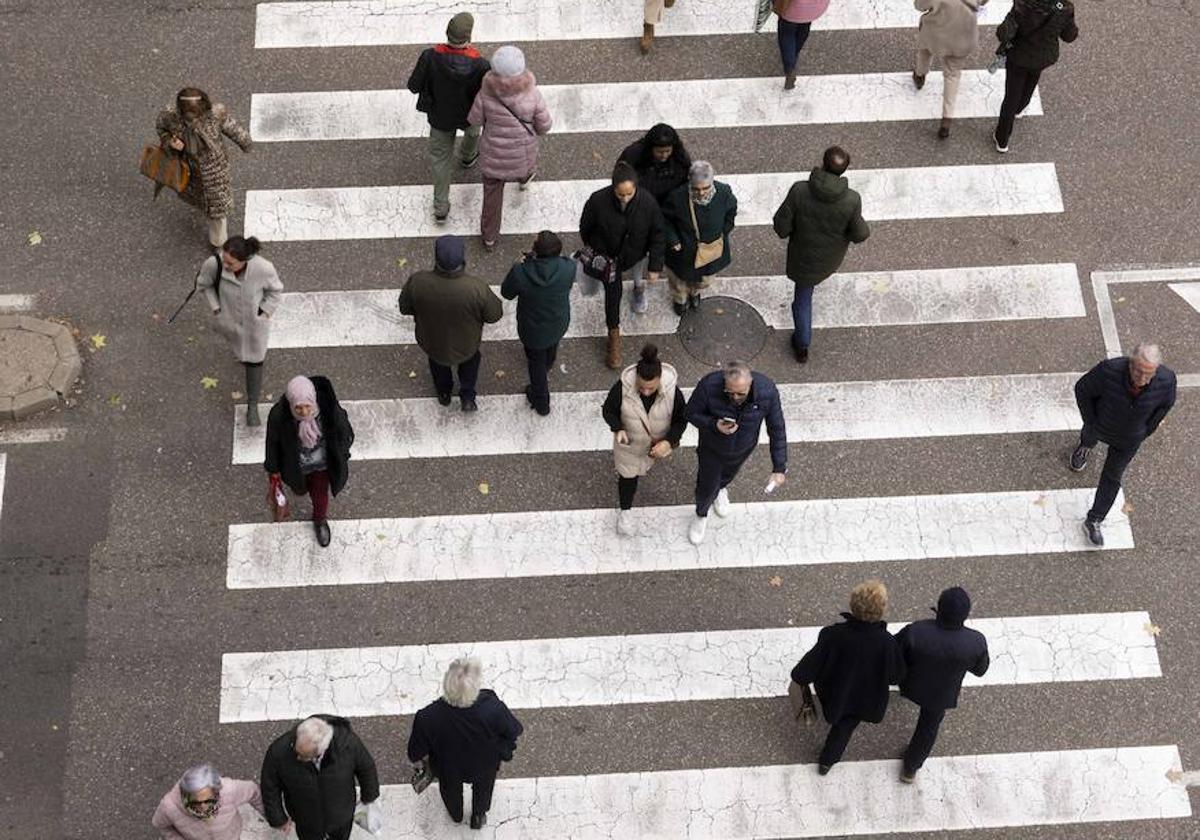 Varias personas cruzan el paso de peatones de la calle San Ildefonso.