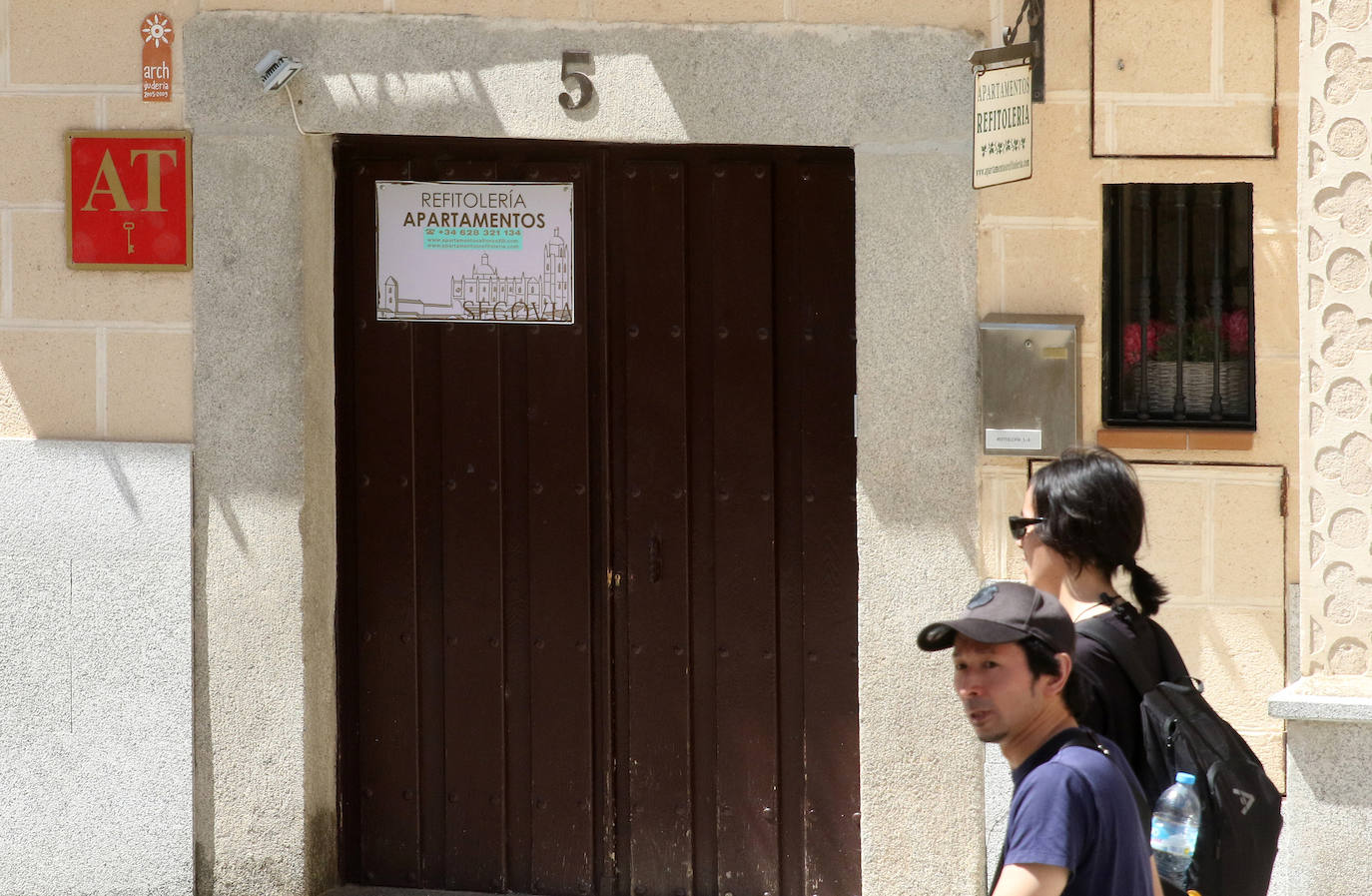 Dos turistas caminan junto a la entrada a un piso turístico en Segovia.