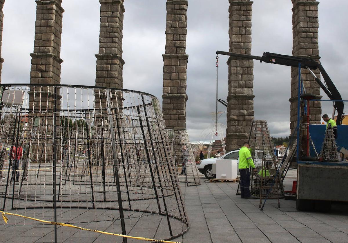 Varios operarios trabajan en la instalación de un cono navideño en la plaza del Azoguejo.