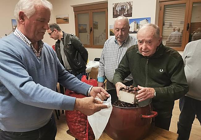 Isidoro Baraja repartiendo las castañas a Paco Real, uno de los cofrades