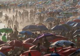 Los brasileños se resguardan del calor en la playa mediante sombrillas y constantes baños en el mar