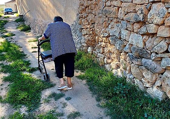 Una vecina pasea con su andador por una de las calles de Tanarro.