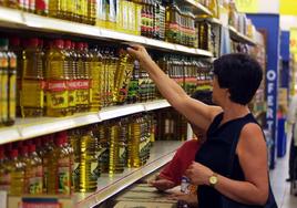 Una mujer compra aceite en un supermercado.