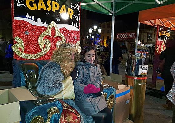 El Rey Gaspar con una niña en una Cabalgata de Aguilar.
