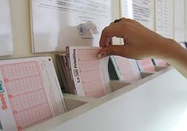Una mujer coge un boleto en una administración de lotería.