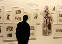 Un visitante observa viñetas colgadas en la exposición.