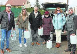 Vecinos de Las Jarillas llegan a sus casas cargados de garrafas de agua.