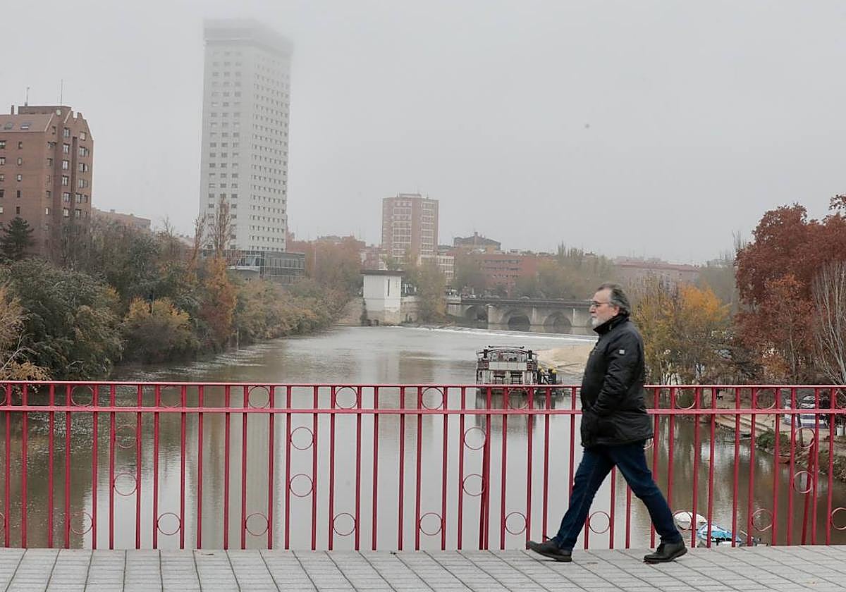 Un hombre cruza el puente de Poniente en una mañana de niebla y frío.