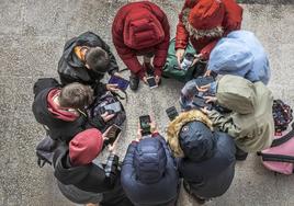 Un grupo de adolescentes consulta sus teléfonos móviles.