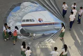 Un grupo de escolares filipinos observa un enorme mural del vuelo MH370 pintado en el suelo del colegio.