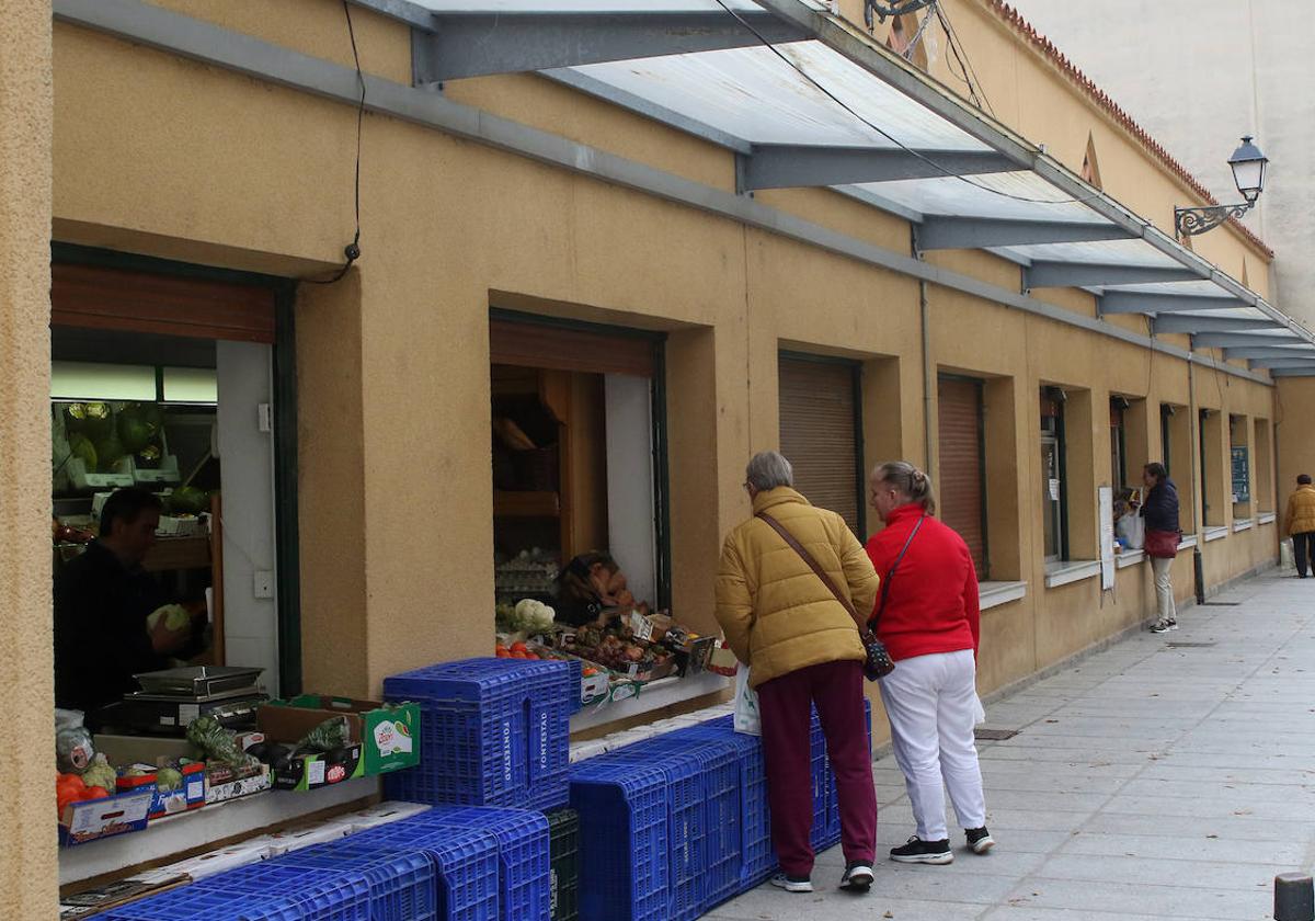 Varias personas compran en los puestos del mercado de Los Huertos.