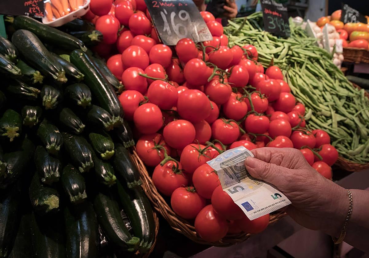 Una consumidora paga una compra en el Mercado de la Mercé, en Barcelona,