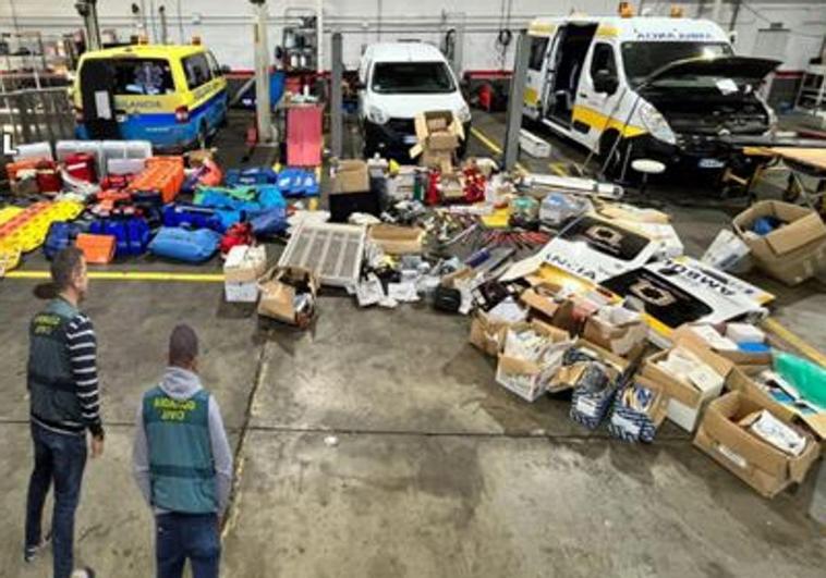 Dos agentes de la Guardia Civil junto al material y los vehículos incautados.