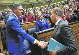 Alberto Núñez Feijóo se acerca al escaño de Pedro Sánchez para felicitarle por su investidura como presidente del Gobierno.