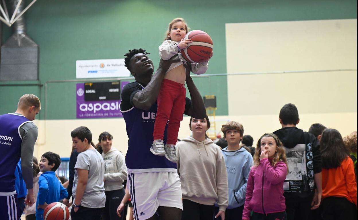 Belemene ayuda a una niña a lanzar a canasta en el entrenamiento navideño celebrado en el frontón. 