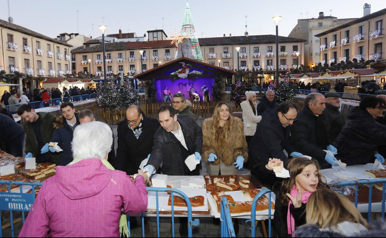 El alcalde de Palencia acompañado del resto de representantes municipales entregan las porciones del roscón navideño, este martes en la Plaza Mayor. 