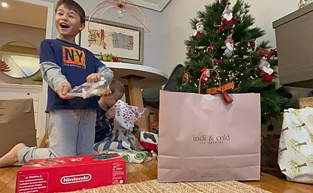 Gonzalo y Álvaro desenvuelven los paquetes con regalos junto al árbol de Navidad.