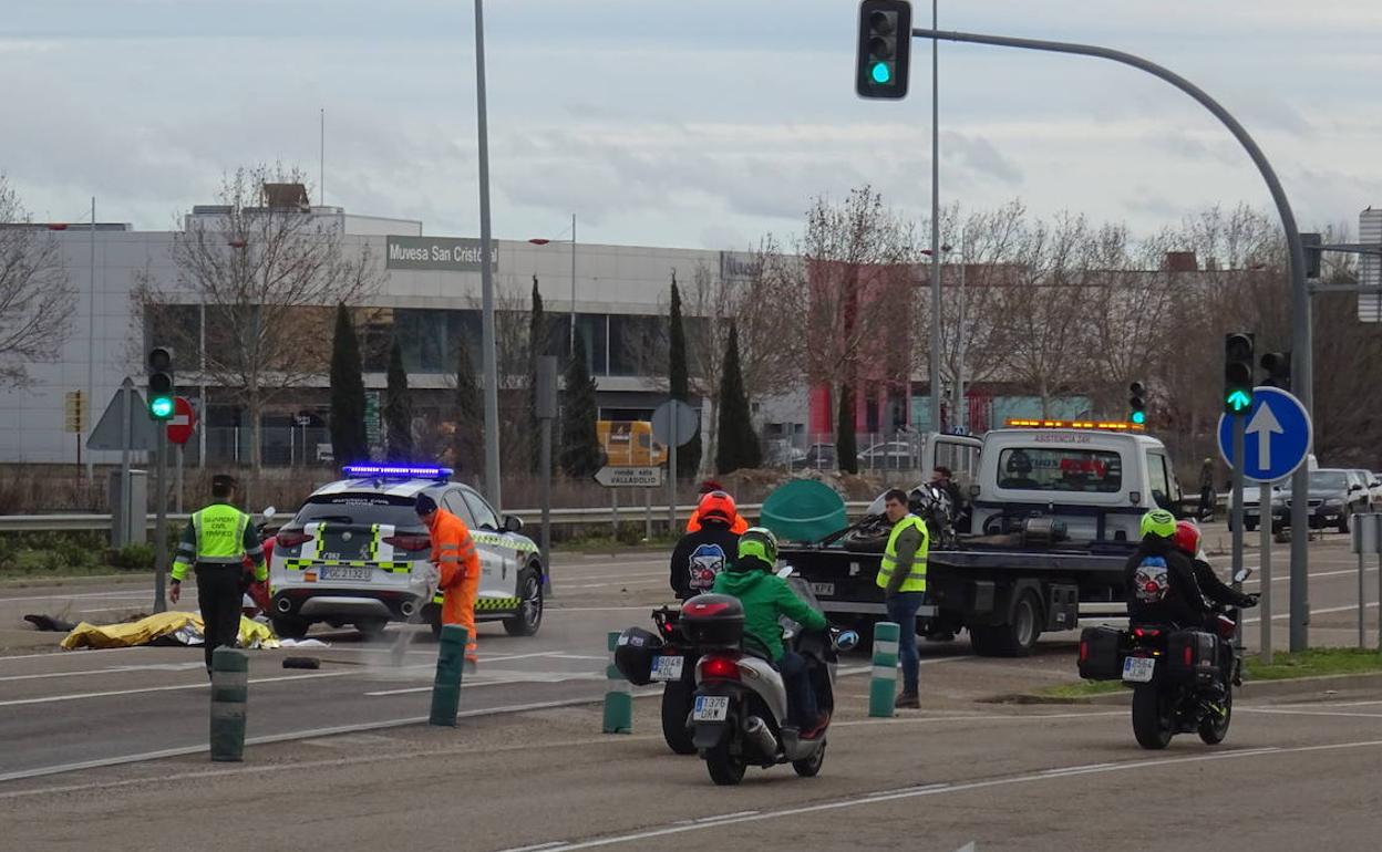 Un grupo de motorista pasa ante la moto siniestrado y el cuerpo de la víctima. 