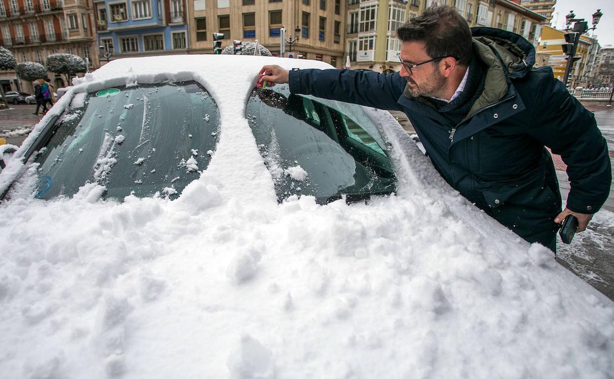 Un hombre retira la nieve de la luna de su vehículo aparcado en Burgos capital durante la jornada de este miércoles.