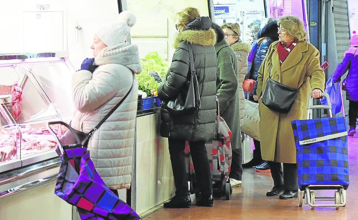 Varias mujeres compran productos frescos en distintos puestos de la Plaza de Abastos, este jueves. 