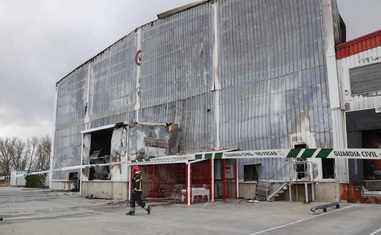 Un bombero revisa el exterior de la fábrica quemada.