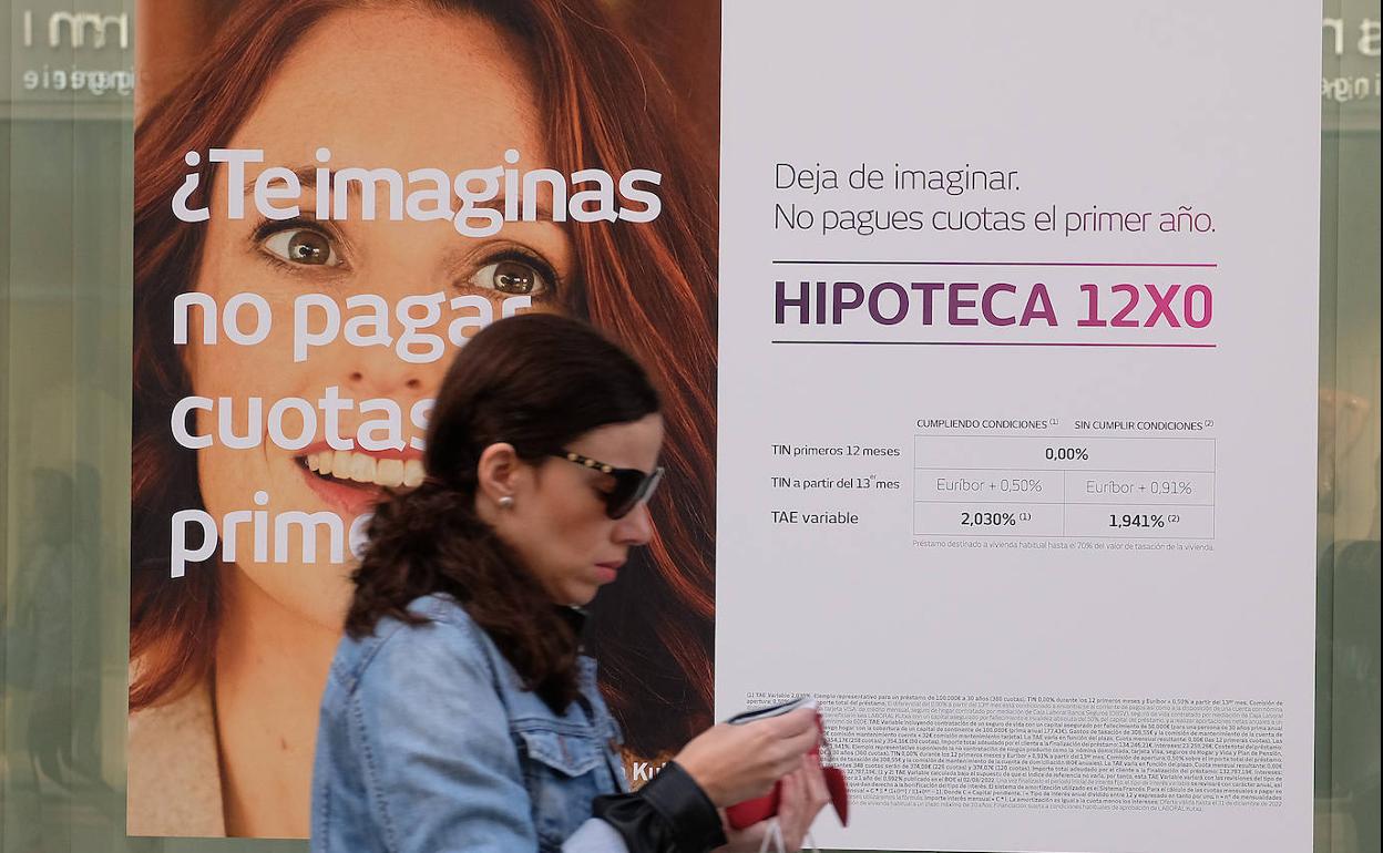 Una mujer pasa por delante de un cartel que publicita una hipoteca.