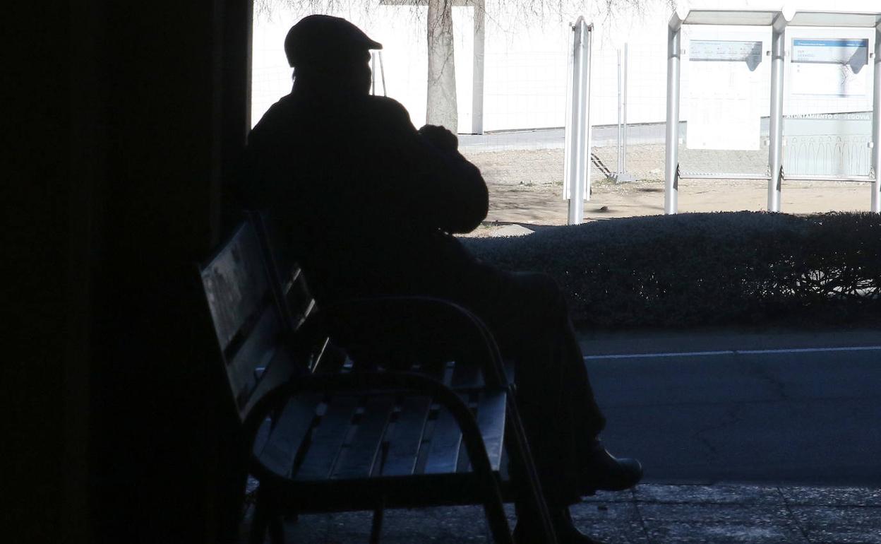 Un hombre descansa en un banco de la vía pública.