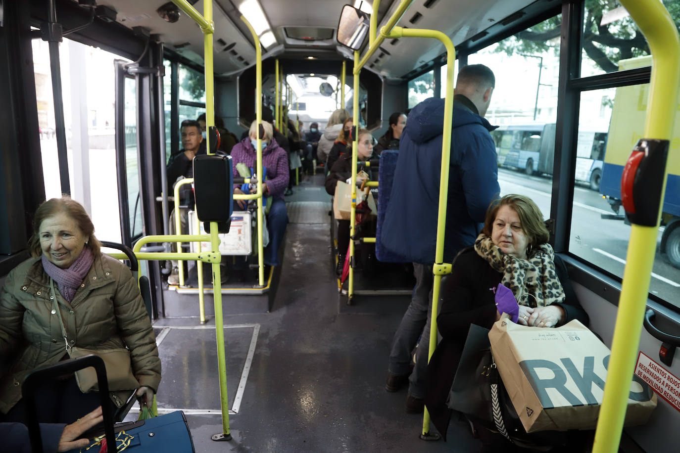 Varias personas con y sin mascarillas en el interior de un autobús urbano.