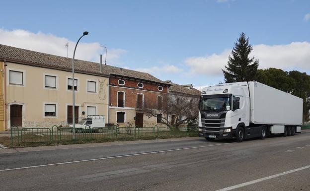 Imagen principal - Un camión circula por la carretera nacional al paso de Piña de Campos. Abajo, indicaciones de carretera cortada en la rotonda de acceso a Frómista y un vecino en el bar del pueblo..