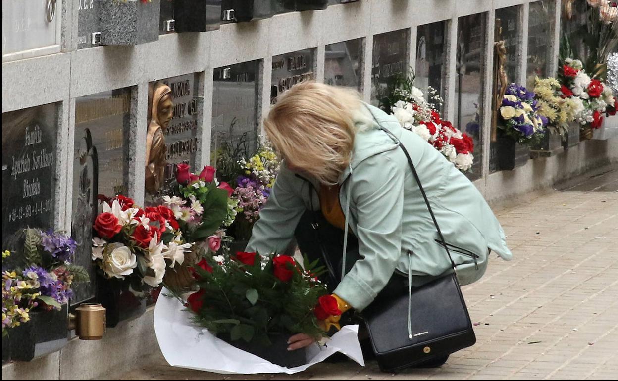 Una mujer deposita un ramo de flores en el cementerio de Segovia. 