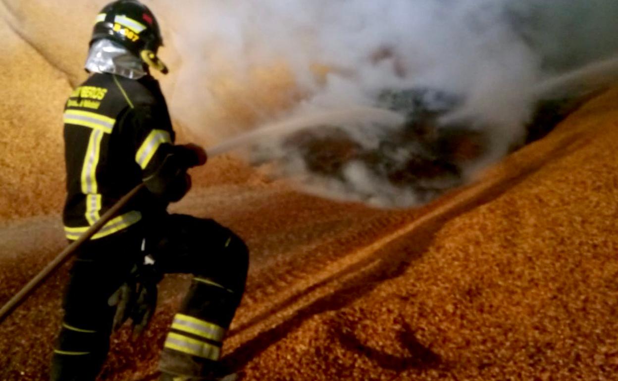 Un bombero del parque de Medina del Campo extingue el incendio en la nave de maíz. 