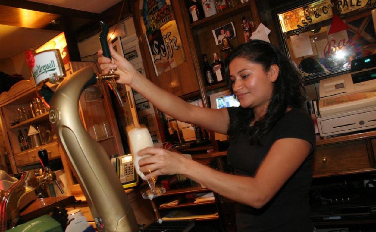 Una joven ecuatoriana que trabaja como camarera tira una caña de cerveza.