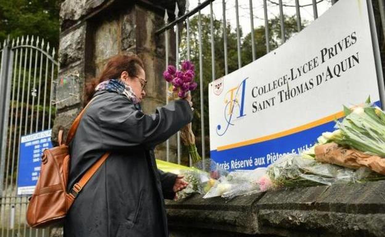 Una mujer coloca un ramo de flores en la entrada del centro en que fue acuchillada mortalmente el miércoles la profeosra Agnès Lassalle