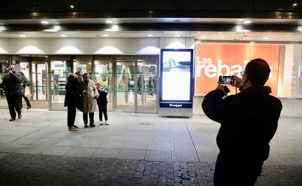 Un hombre fotografía a una mujer con sus nietos delante de la fachada de El Corte Inglés de Constitución.