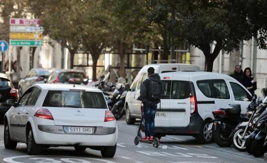 Un hombre circula con su patinete por un carril bus. 