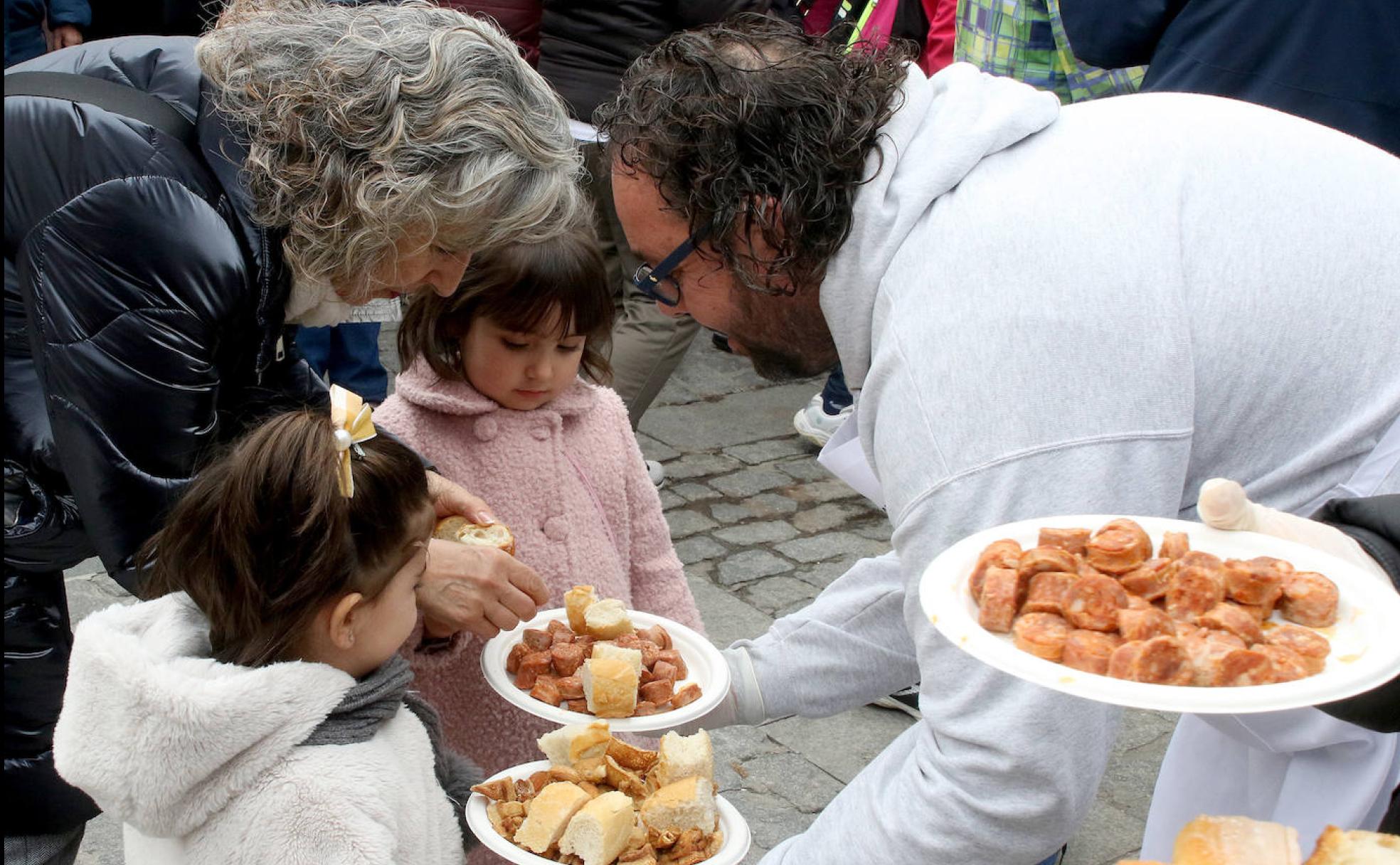 Félix Maroto, presidente de La Parrilla, ofrece un plato con chorizo a dos niñas en la degustación de este domingo. 
