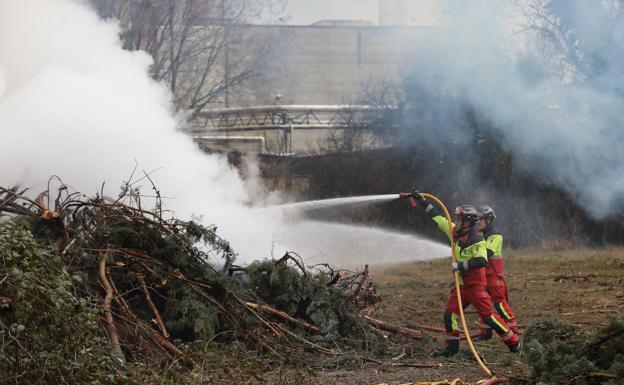 Dos bomberos dirigen la quema controlada este lunes.
