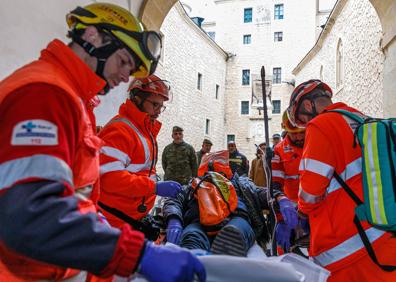 Imagen secundaria 1 - Arriba, bomberos con una manguera en una de las buhardillas del ala norte de la fortaleza. Abajo, personal sanitario con el trabajador afectado por una hipotética inhalación de humo. Al lado, imagen de la cámara térmica. 