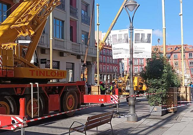 Los operarios retiran las luces navideñas junto al tramo acordonado por el hundimiento de la calzada en la calle Santiago.