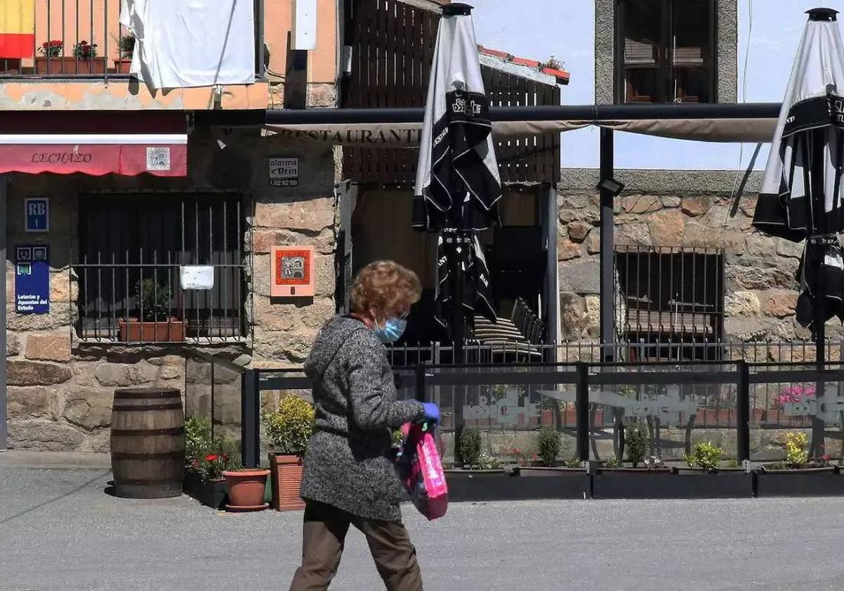 Una mujer pasa por delante del restaurante Lobiche, en Navafría, que ha repartido tres décimos del primer premio de la Lotería de este sábado.