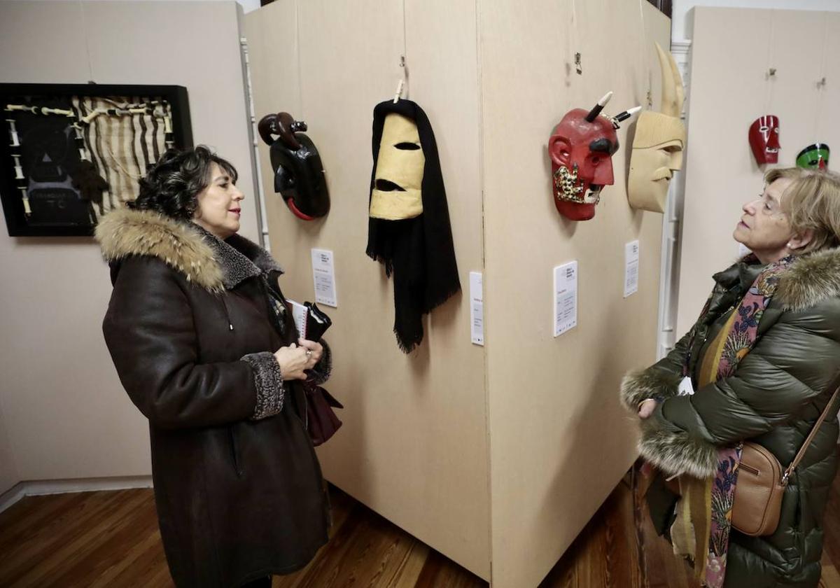 Dos visitantes observan algunas de las máscaras de la exposición.