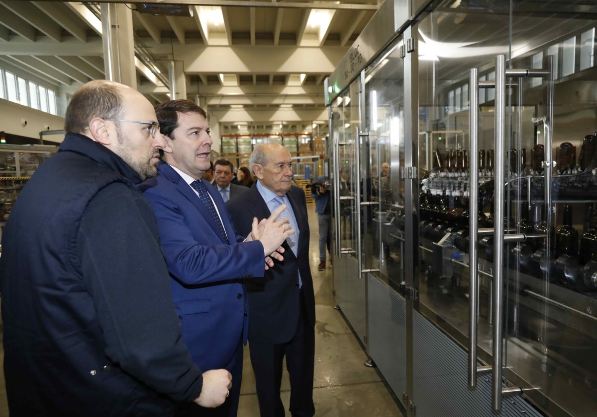 Alfonso Fernández Mañueco, junto al presidente de Protos, Edmundo Bayón -derecha de la imagen- atienden las explicaciones de un trabajador de Protos -en primer plano-, en la planta embotelladora integrada en las instalaciones inauguradas.