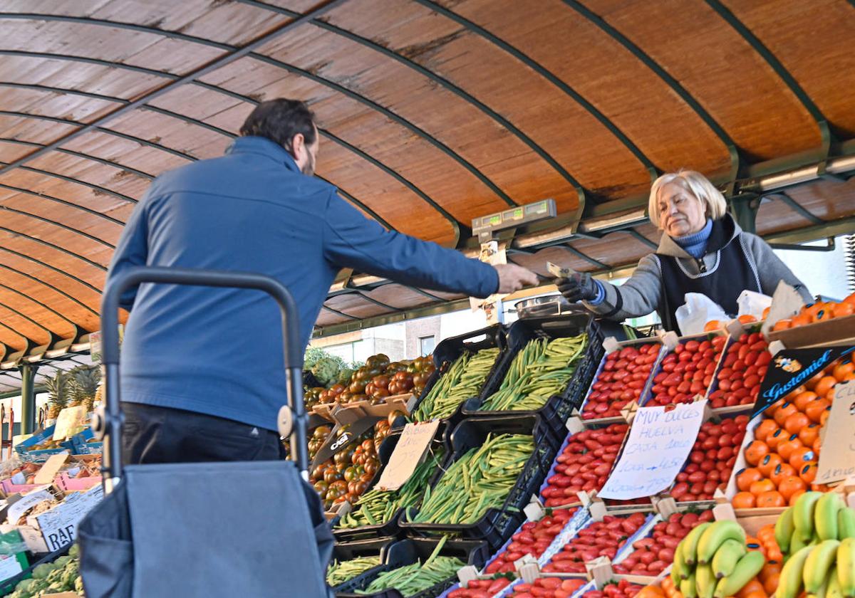 Un cliente paga su compra a una frutera del mercado.