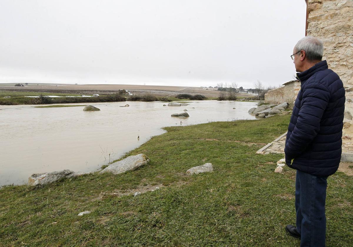 Un hombre observa la crecida de un arroyo, este sábado, a su paso por Balisa.