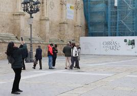 Una mujer fotografía a otra delante de la Catedral y junto a otro grupo de turistas.