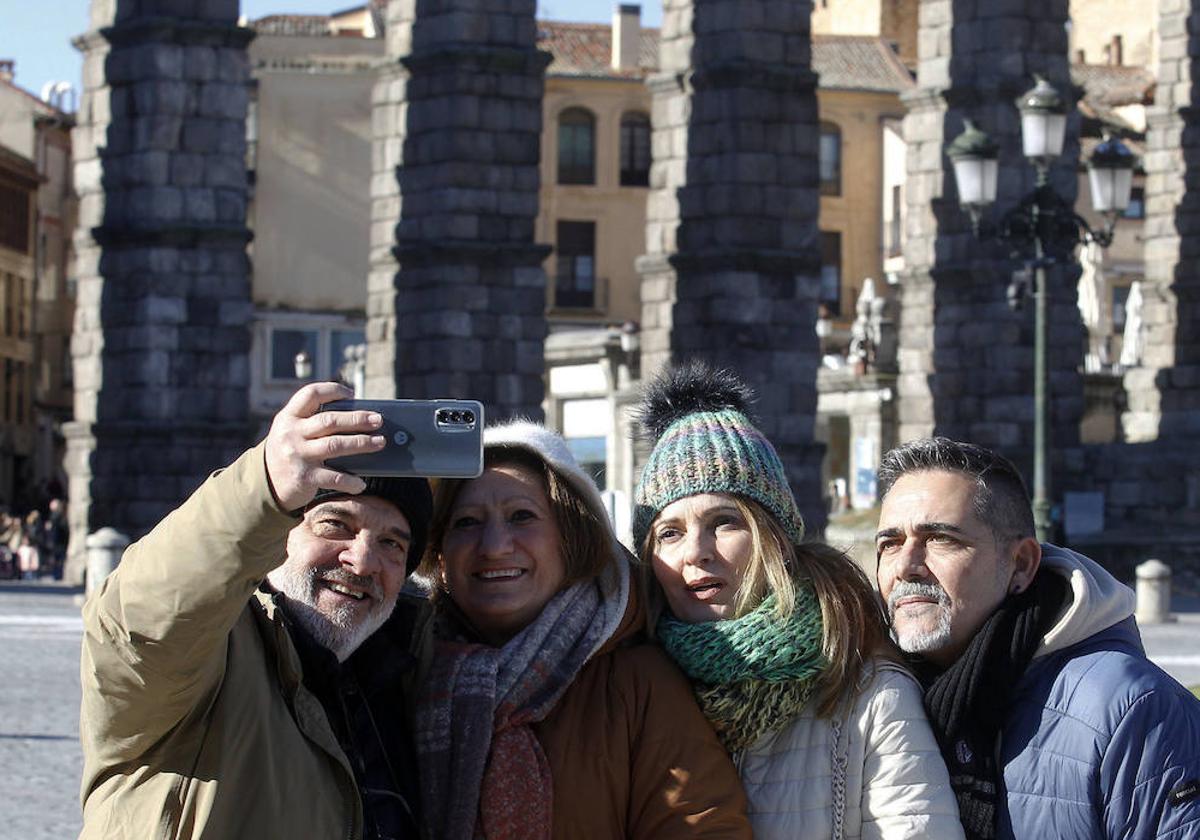 Unos turistas se sacan una foto con el Acueducto de Segovia al fondo.