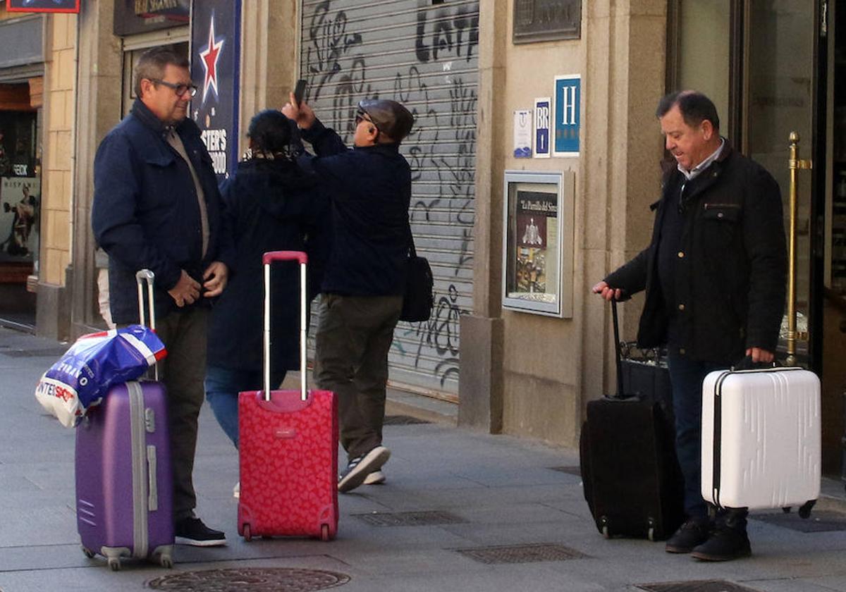 Turistas con maletas a la entrada de un hotel en el centro de Segovia.