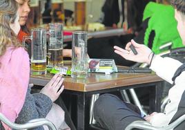 Unos jóvenes en una terraza con los paquetes de tabaco de liar en la mesa.