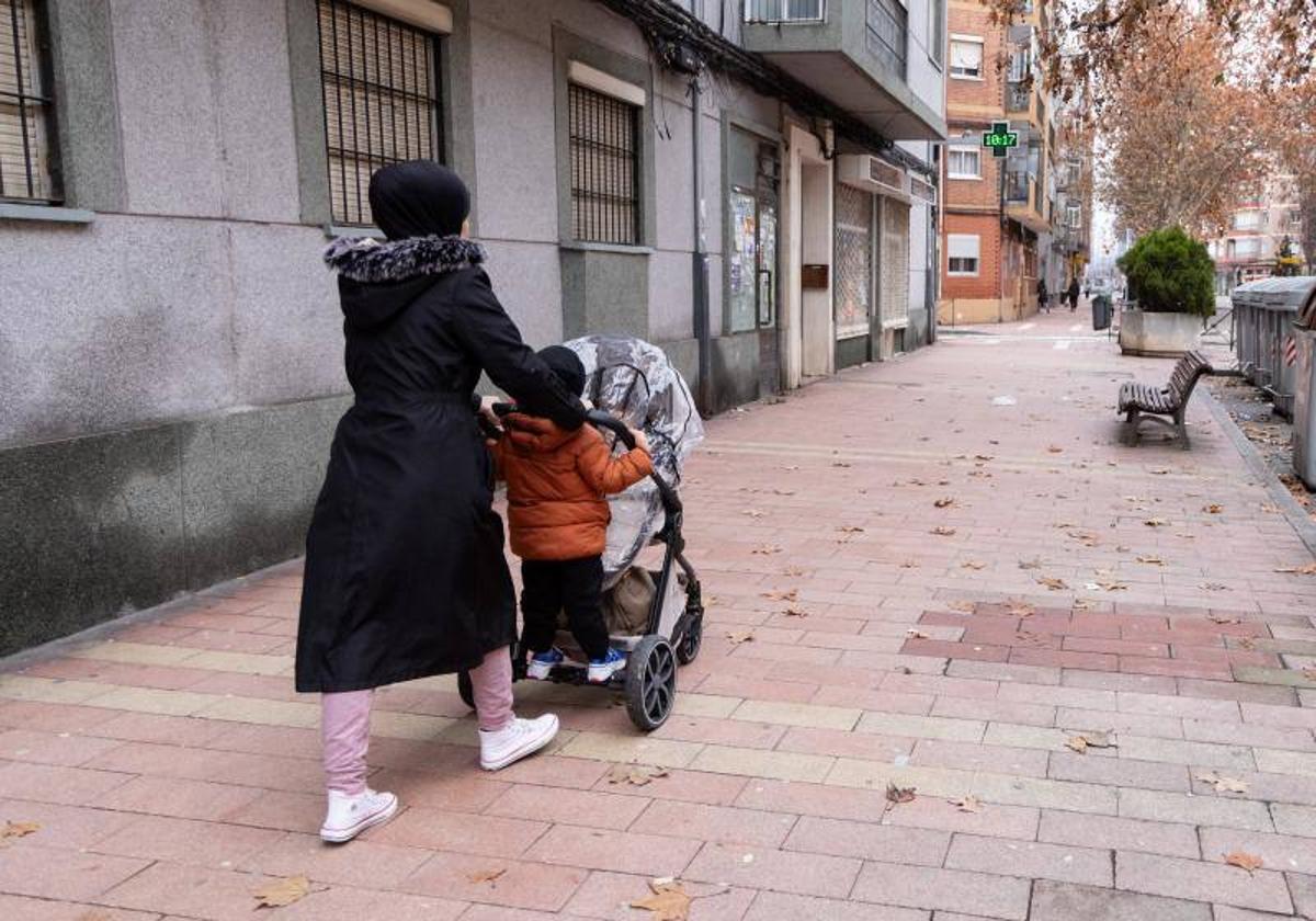 Una mujer pasea por dos niños por el barrio de Las Delicias de Valladolid.